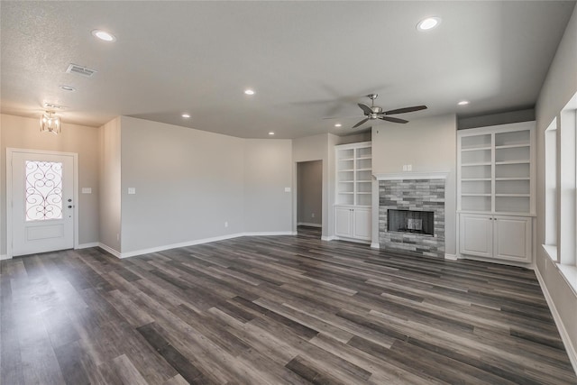 unfurnished living room featuring dark wood-type flooring, a textured ceiling, a fireplace, and ceiling fan with notable chandelier