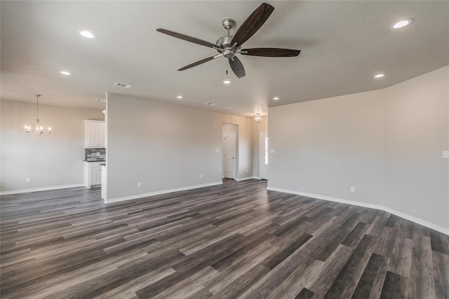 unfurnished living room with ceiling fan with notable chandelier and dark hardwood / wood-style flooring