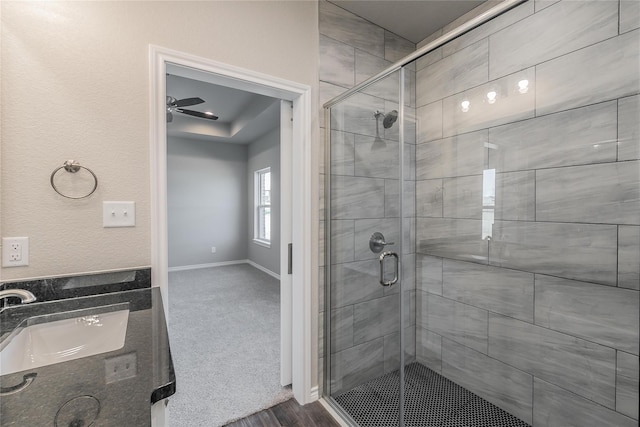 bathroom with a shower with door, ceiling fan, and sink