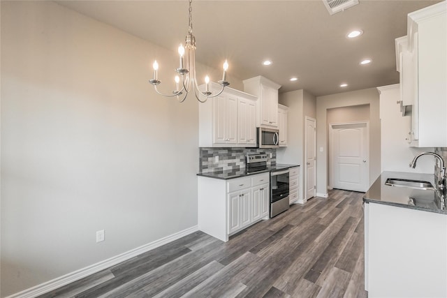 kitchen with appliances with stainless steel finishes, white cabinetry, dark hardwood / wood-style floors, decorative light fixtures, and sink