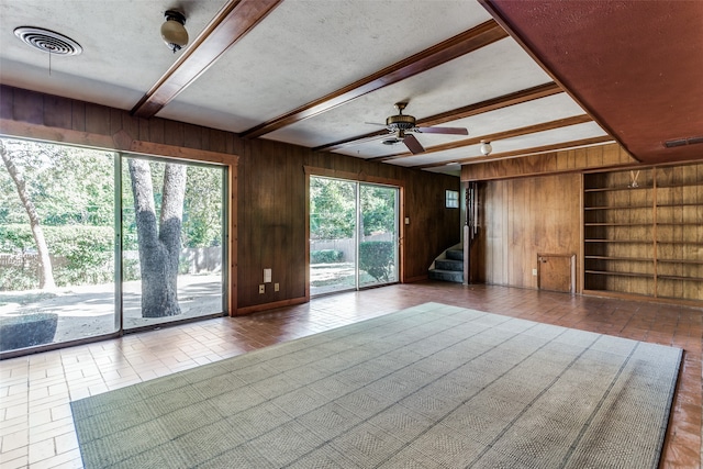 unfurnished living room featuring ceiling fan, a textured ceiling, and wooden walls