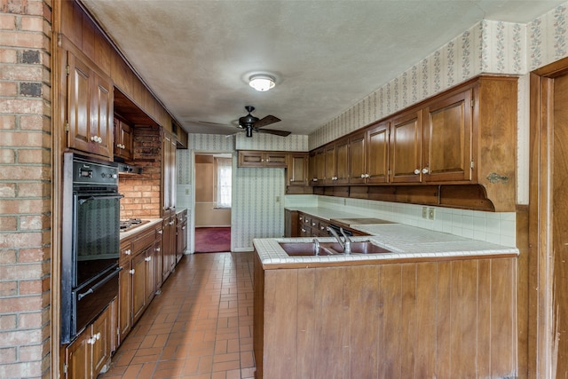 kitchen featuring oven, kitchen peninsula, ceiling fan, a textured ceiling, and sink