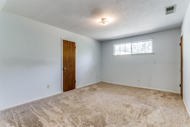 unfurnished room featuring a textured ceiling and carpet