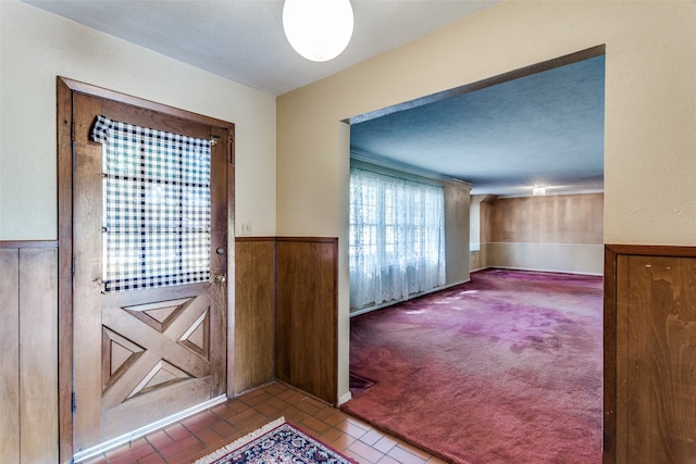 carpeted entrance foyer with wooden walls