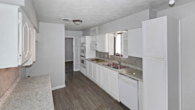 kitchen with dark hardwood / wood-style floors, sink, white cabinets, light stone counters, and white appliances