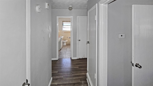 corridor with a textured ceiling and dark hardwood / wood-style flooring