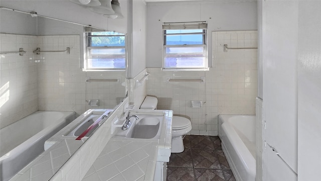 full bathroom with toilet, tiled shower / bath, vanity, and tile walls