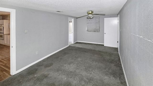 unfurnished room featuring ceiling fan, a textured ceiling, and dark carpet