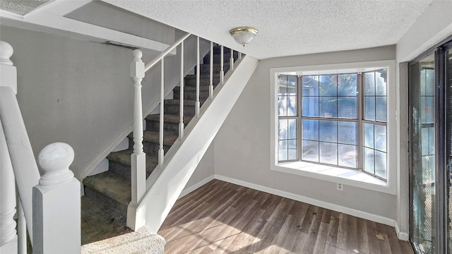 staircase with a textured ceiling and hardwood / wood-style flooring