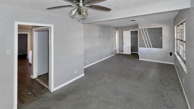 empty room with beamed ceiling, dark colored carpet, and ceiling fan