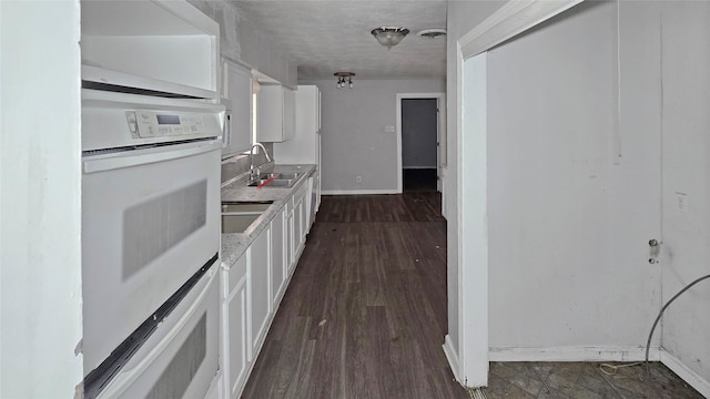 kitchen featuring white cabinetry, double oven, sink, and dark hardwood / wood-style floors