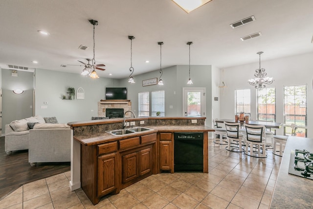 kitchen featuring dishwasher, ceiling fan with notable chandelier, sink, light tile patterned floors, and an island with sink