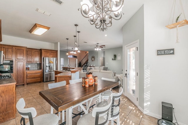 dining space with ceiling fan with notable chandelier, light tile patterned floors, and sink