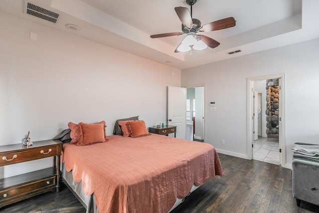 bedroom featuring a raised ceiling, ceiling fan, and dark wood-type flooring