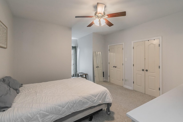 bedroom featuring ceiling fan, light carpet, and two closets