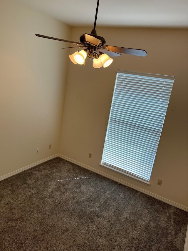 spare room with ceiling fan and dark colored carpet