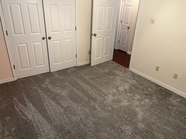 unfurnished bedroom with dark carpet and a closet