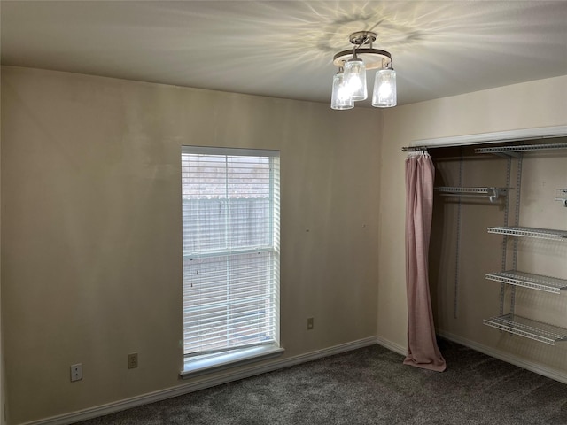 unfurnished bedroom featuring dark carpet and a closet