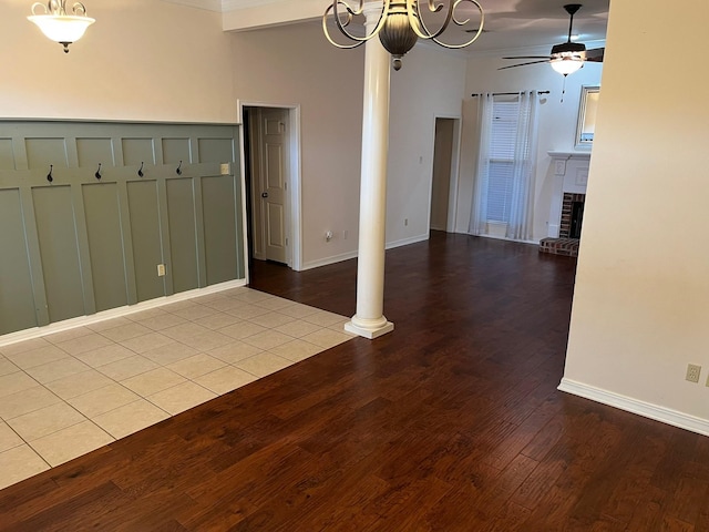 empty room featuring decorative columns, ceiling fan, a fireplace, and light hardwood / wood-style floors