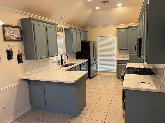 kitchen featuring sink, vaulted ceiling, light tile patterned floors, appliances with stainless steel finishes, and kitchen peninsula