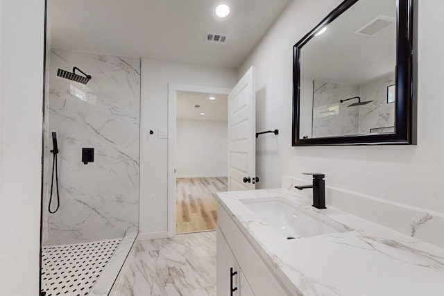 bathroom featuring vanity, a tile shower, and wood-type flooring