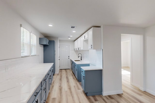 kitchen with light hardwood / wood-style floors, white cabinetry, tasteful backsplash, and blue cabinetry