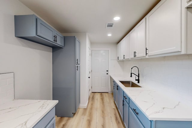 kitchen featuring light hardwood / wood-style floors, tasteful backsplash, sink, and white cabinets