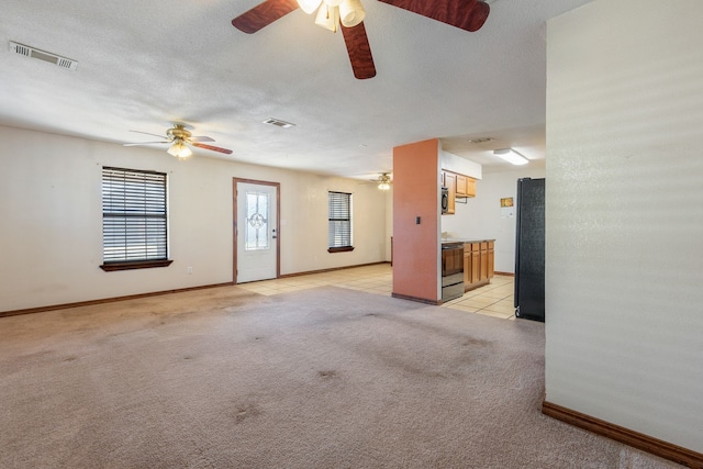 unfurnished living room featuring light carpet, a textured ceiling, and ceiling fan