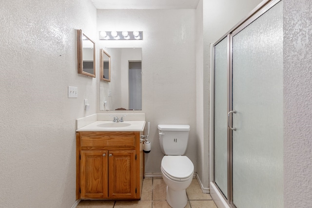 bathroom featuring a shower with door, vanity, toilet, and tile patterned flooring