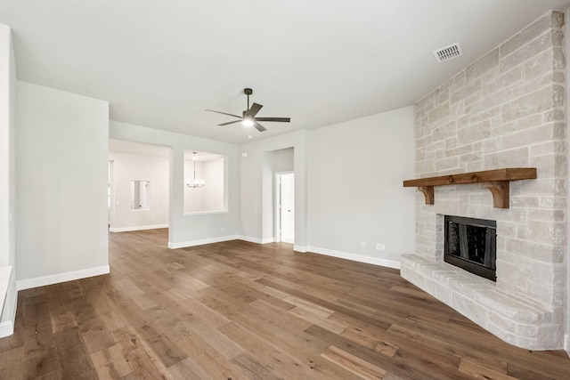 unfurnished living room featuring hardwood / wood-style flooring, ceiling fan, and a fireplace