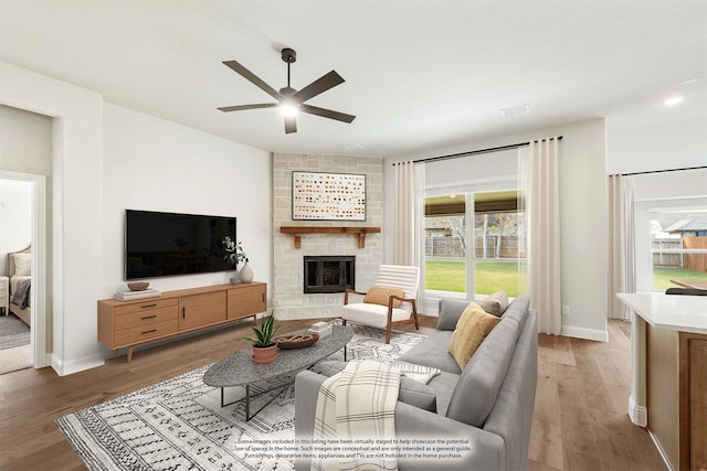 living room with hardwood / wood-style flooring, ceiling fan, and a fireplace