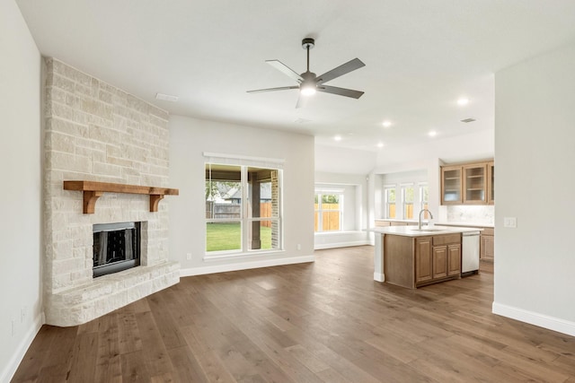 unfurnished living room featuring a fireplace, hardwood / wood-style floors, ceiling fan, and sink