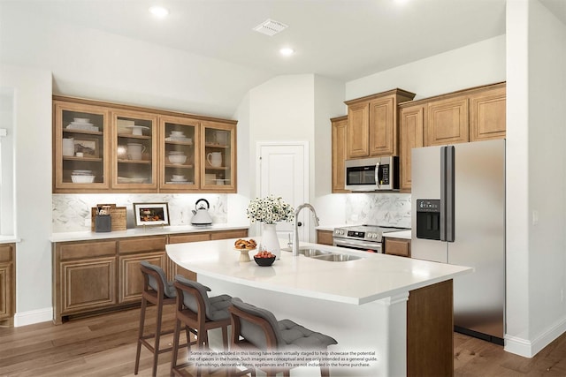 kitchen with stainless steel appliances, sink, a kitchen breakfast bar, and a kitchen island with sink