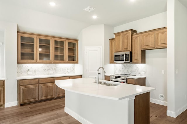 kitchen featuring decorative backsplash, a kitchen island with sink, sink, and stainless steel appliances