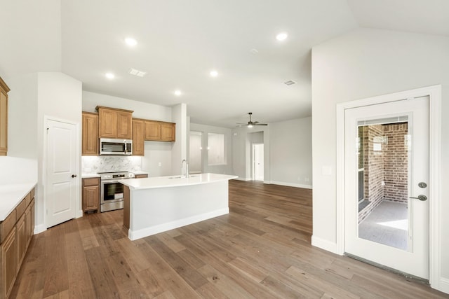 kitchen featuring a kitchen island with sink, sink, vaulted ceiling, ceiling fan, and appliances with stainless steel finishes