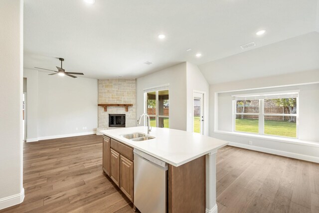 kitchen featuring dishwasher, sink, an island with sink, and light wood-type flooring