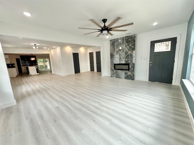 unfurnished living room featuring a fireplace, light wood-type flooring, and ceiling fan