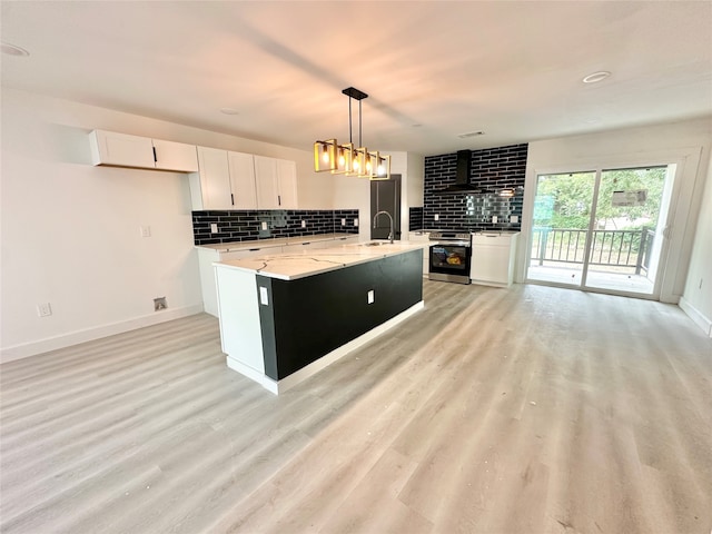 kitchen featuring stainless steel electric stove, white cabinets, sink, and an island with sink