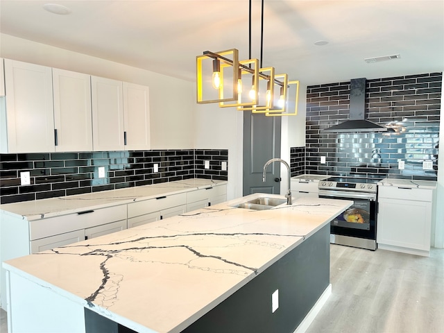 kitchen with wall chimney exhaust hood, sink, electric range, decorative light fixtures, and light wood-type flooring