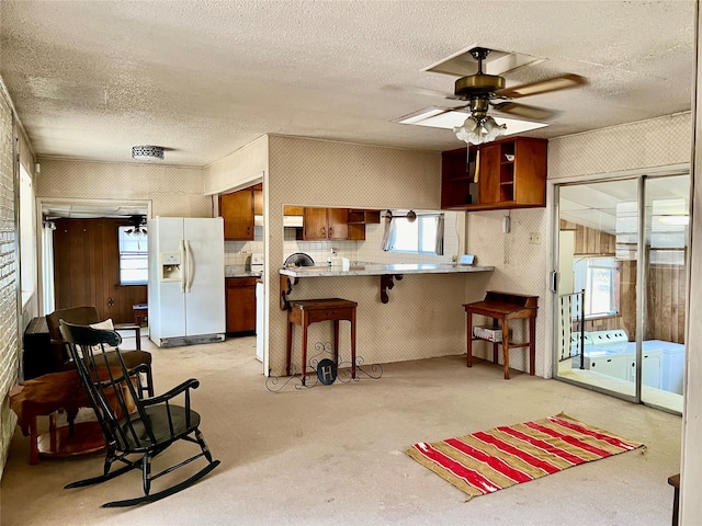 kitchen featuring kitchen peninsula, white refrigerator with ice dispenser, plenty of natural light, and a breakfast bar area