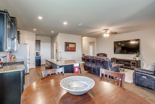 dining room featuring ceiling fan, sink, and light hardwood / wood-style flooring