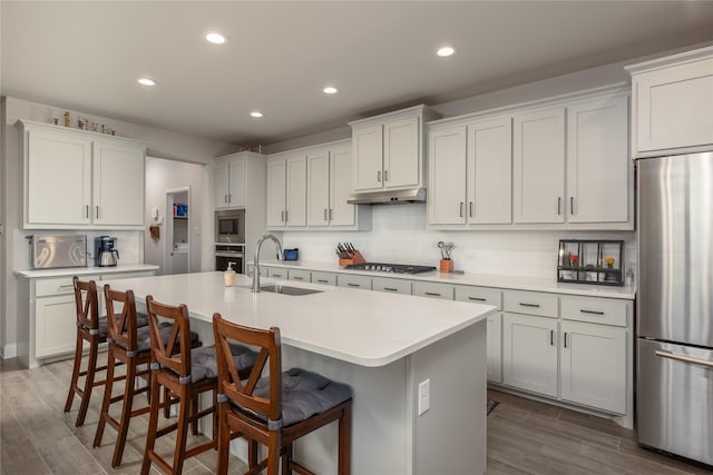 kitchen featuring sink, white cabinetry, appliances with stainless steel finishes, and an island with sink