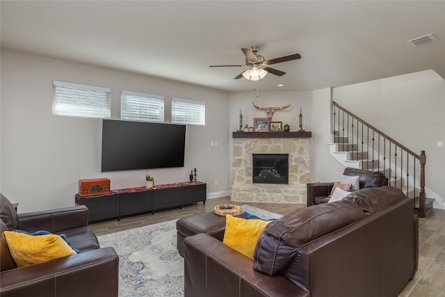 living room with ceiling fan and a stone fireplace