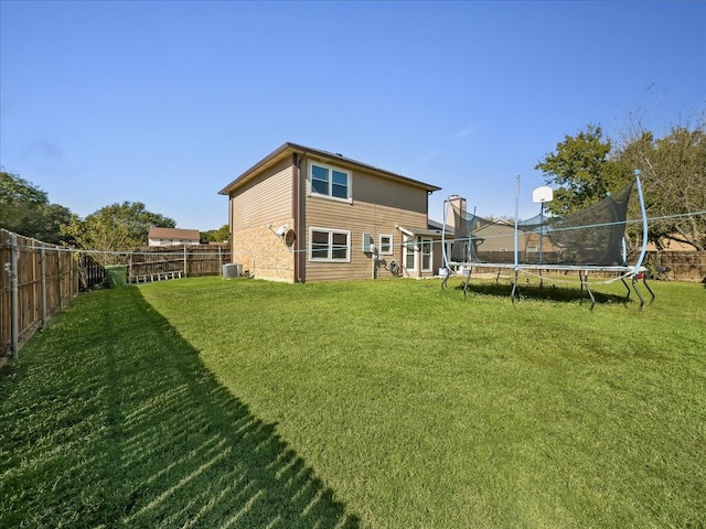 back of property featuring a lawn, cooling unit, and a trampoline