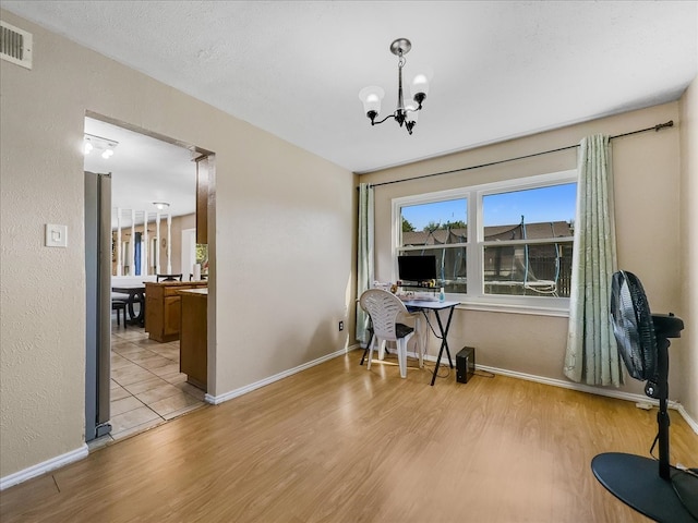 home office featuring light hardwood / wood-style floors and a notable chandelier