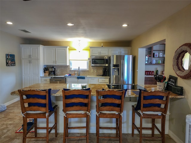 kitchen with sink, a kitchen breakfast bar, appliances with stainless steel finishes, and white cabinetry