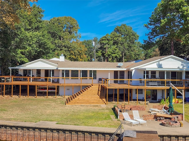 back of property featuring a patio, a deck, a lawn, and a fire pit