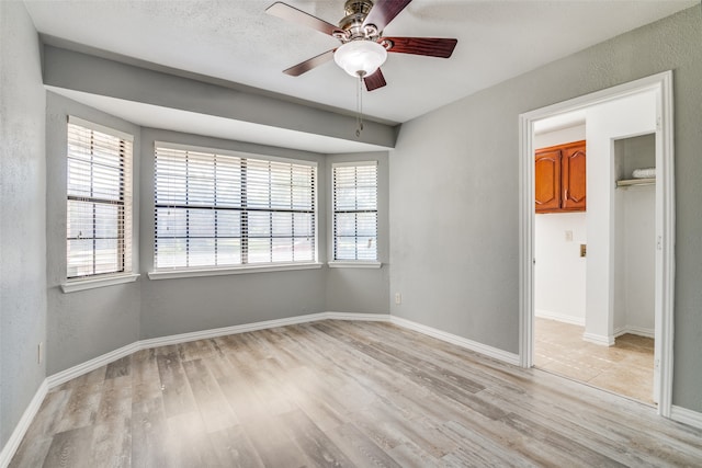 spare room featuring a healthy amount of sunlight, light hardwood / wood-style floors, and ceiling fan