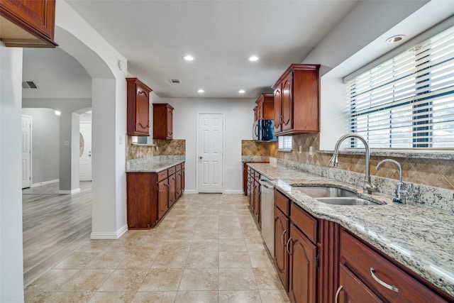 kitchen featuring light stone countertops, light tile patterned flooring, sink, backsplash, and stainless steel dishwasher