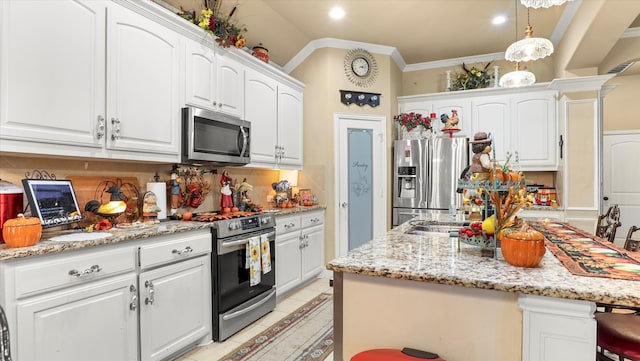 kitchen featuring hanging light fixtures, a kitchen breakfast bar, white cabinetry, stainless steel appliances, and a center island